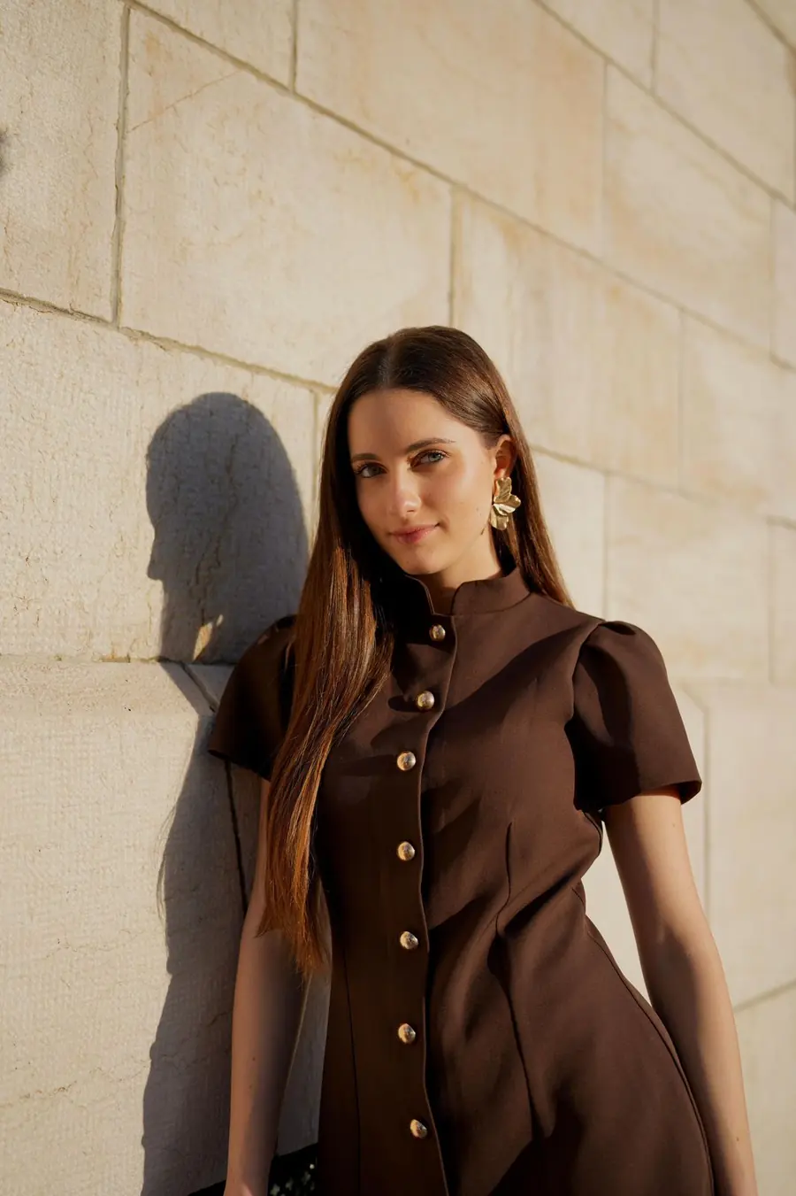 A model in a Pavia dress against a stone wall